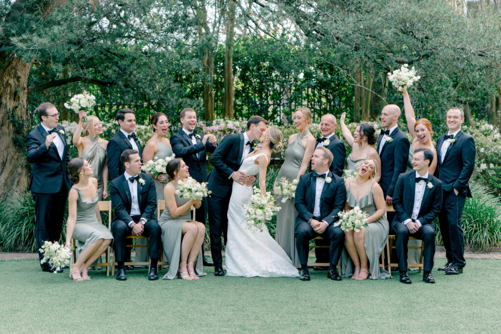 Full bridal party group photo with bride and groom kissing. Bride and groom dip kiss. 
