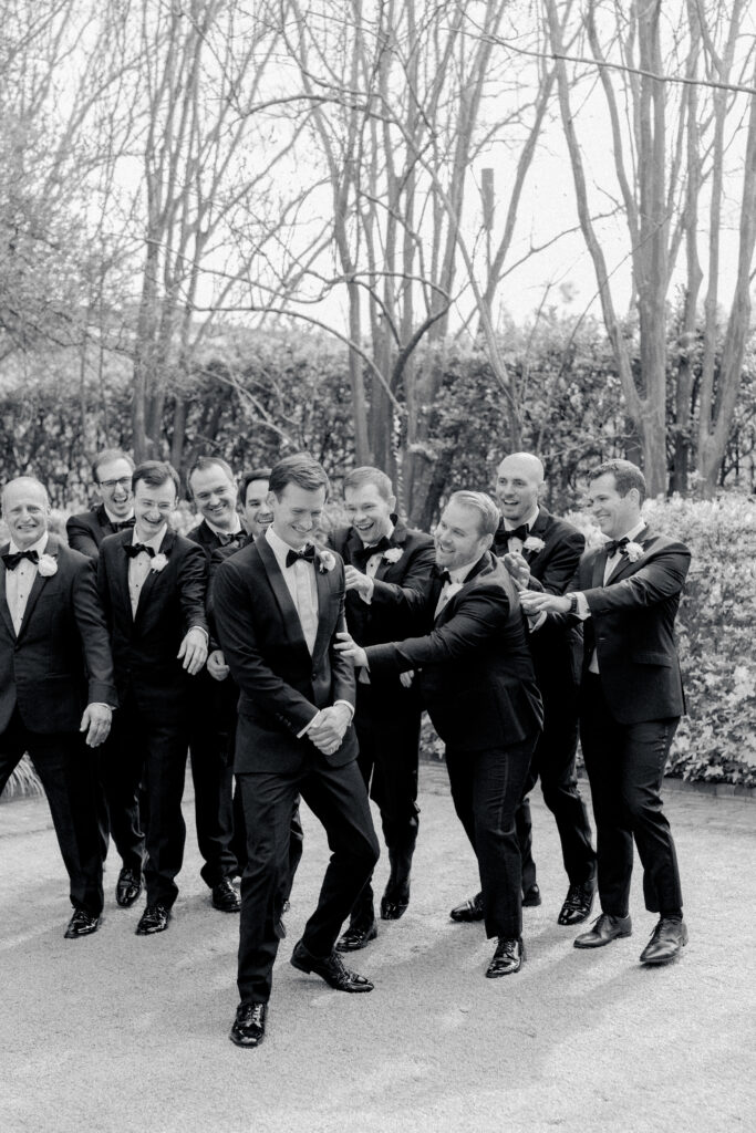 Black and white photo of groom and groomsmen. Fun bridal party photos.