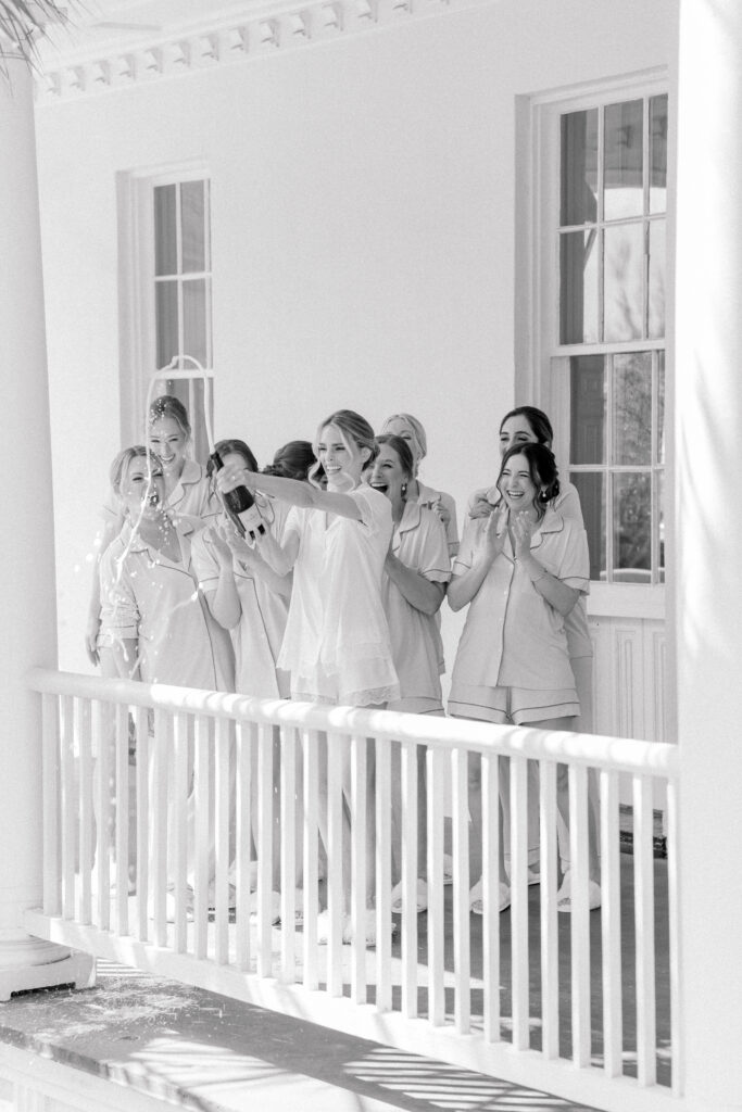 Black and white photo of bride spraying champagne with bridesmaids. 