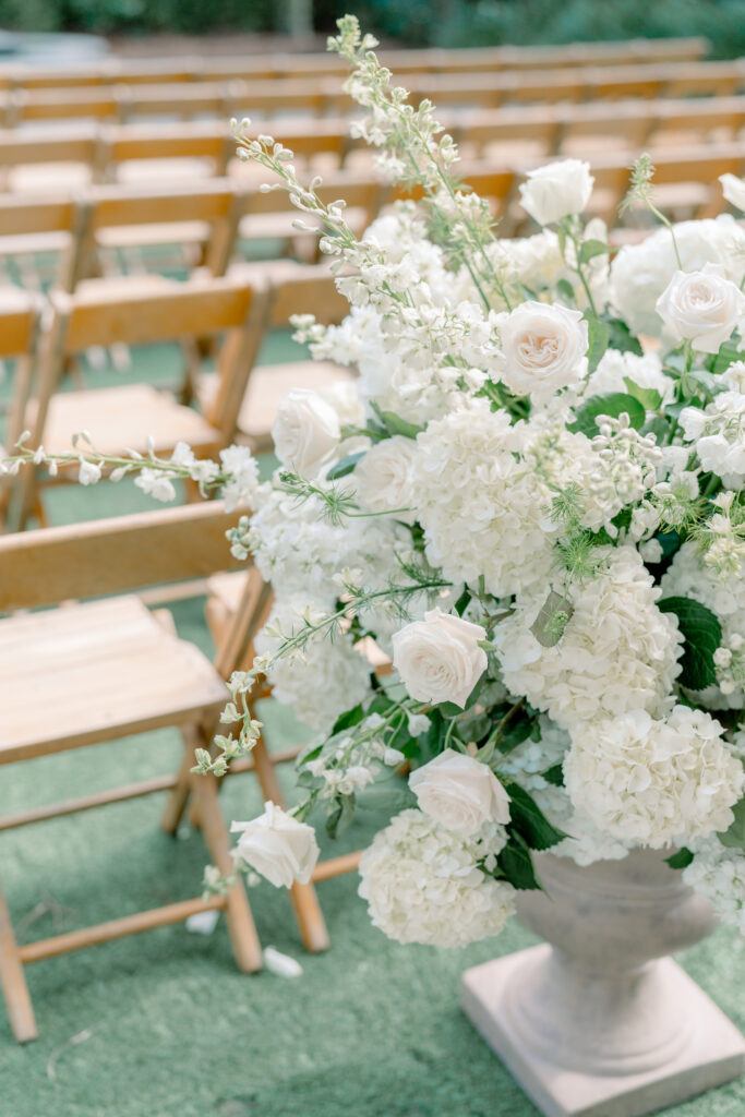White and green wedding ceremony pedestal flowers at the start of the aisle. 