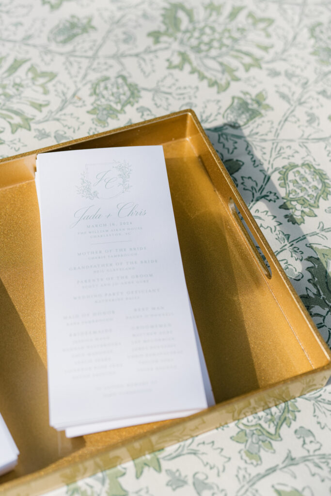 William Aiken House wedding programs in a gold tray on green and white linens. 