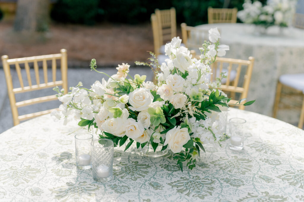 Sun touching table top flowers at William Aiken House outdoor wedding reception. White and green classic flowers. 