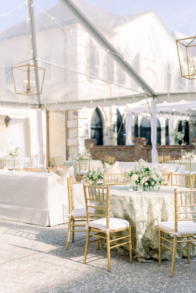 Outdoor open-air wedding reception at William Aiken House. Charleston destination wedding. Gold chairs and chandeliers.
