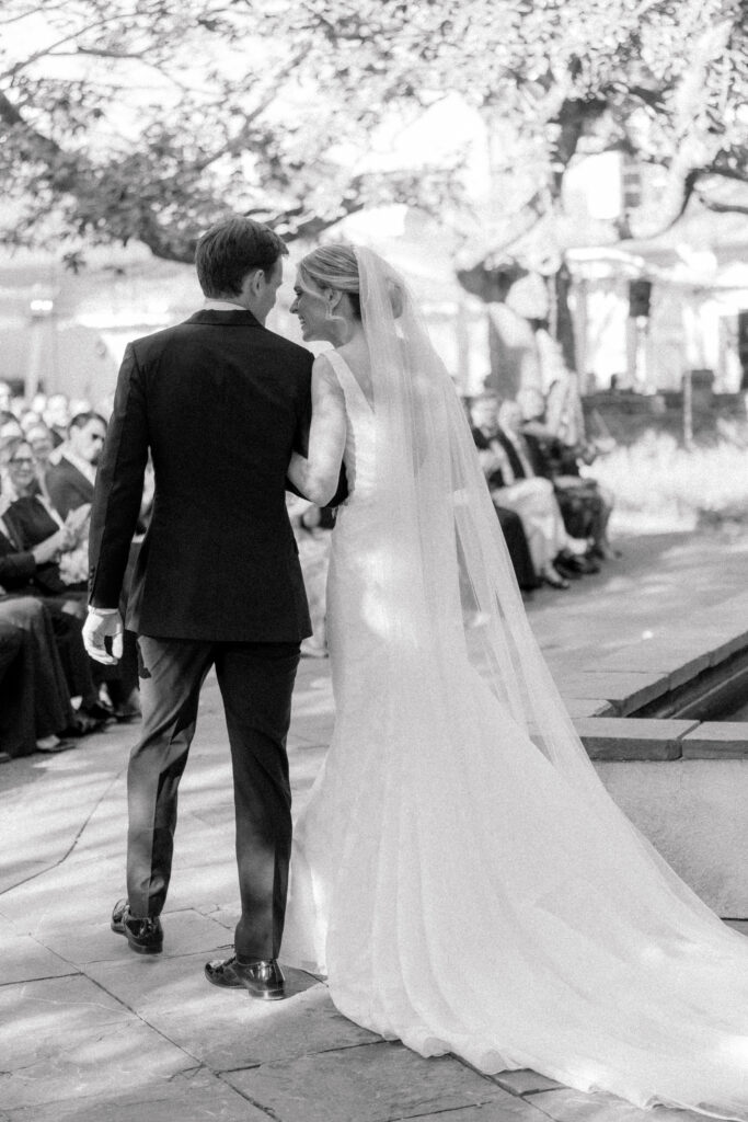 Bride and groom laugh together before walking down the aisle as husband and wife. 