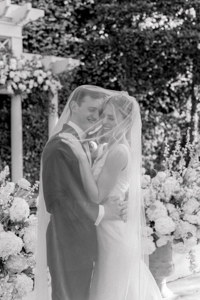 Bride and groom giggling under the veil. Black and white wedding photo. 
