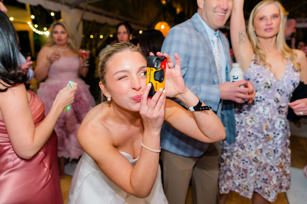 Bride takes a picture with disposable camera on dance floor. 