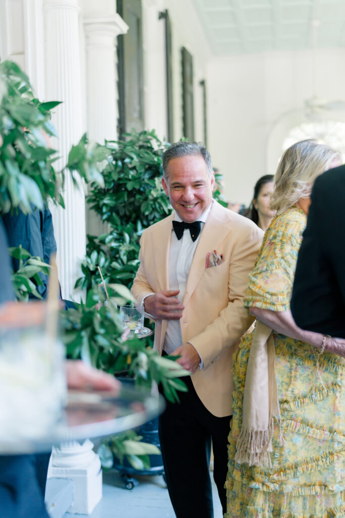 Wedding guest in peach tuxedo jacket at cocktail hour squeezing through the crowd. 