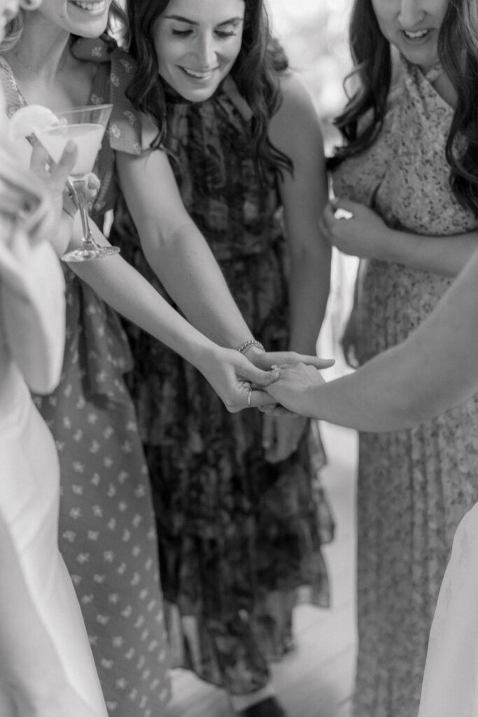 Friends of the bride check out her ring at cocktail hour. Black and white candid wedding photos. 