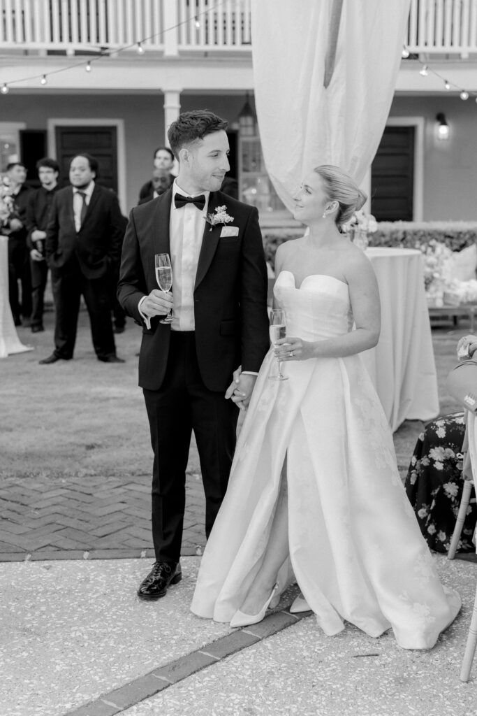 Bride and groom hold hands and look at each other during speeches at spring wedding in Charleston. 