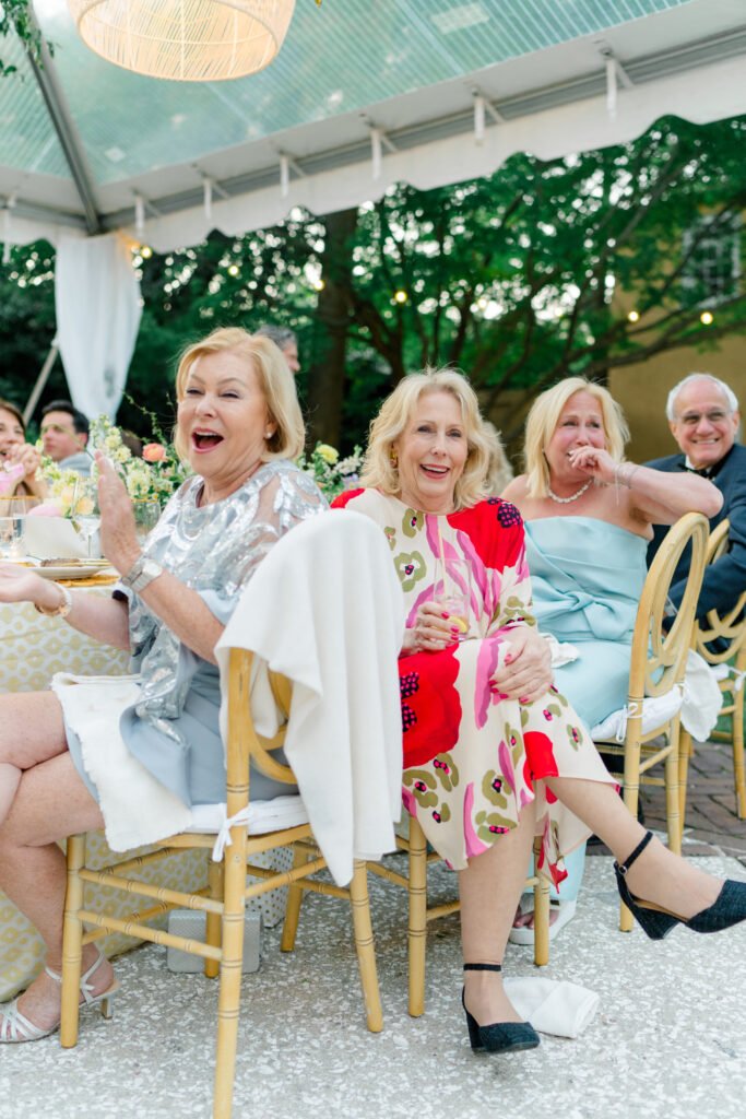 Wedding guests laughing during speeches at Charleston wedding. Bright spring wedding attire. 