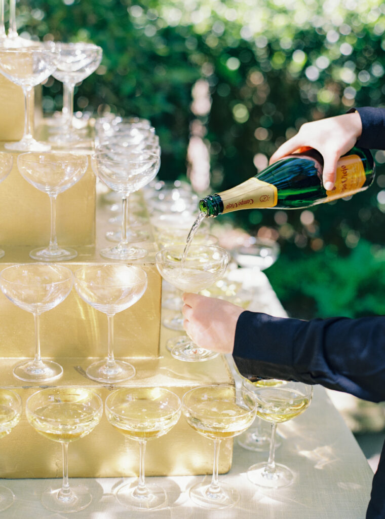 Champagne tower welcoming guests to outdoor garden wedding ceremony. 