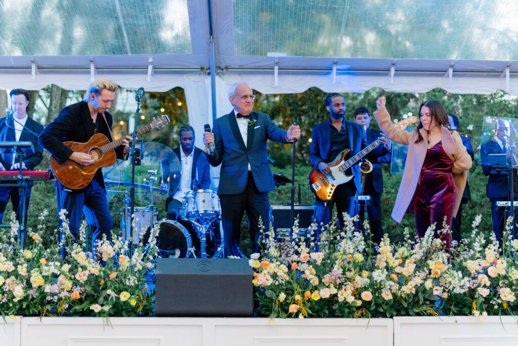 Father of the groom joins the band for live performance during outdoor wedding reception. 