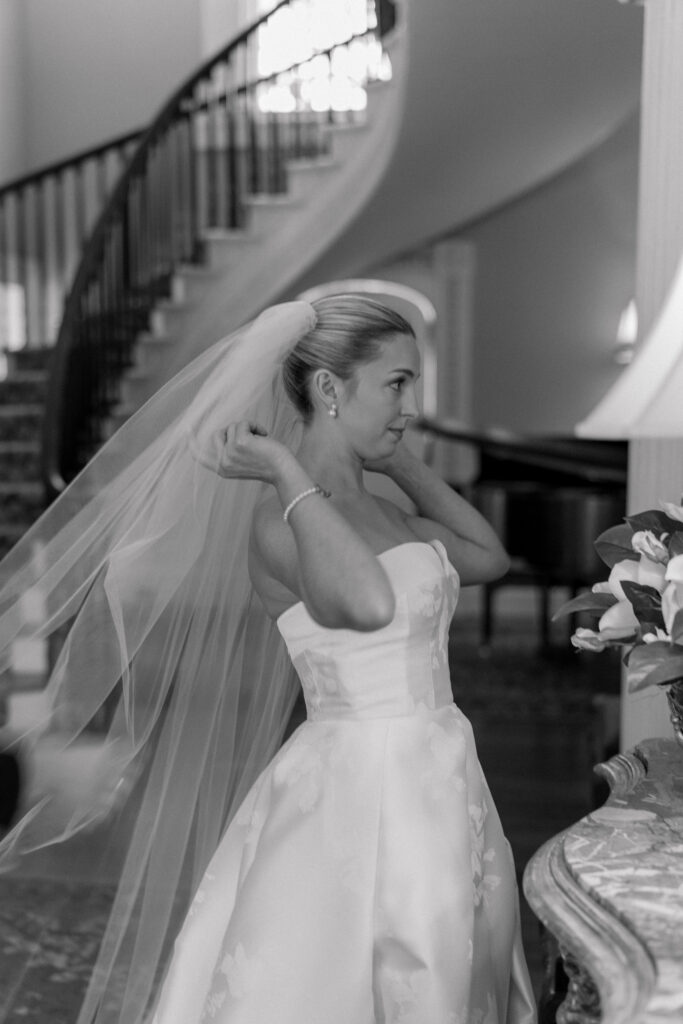 Bride checks her self in the mirror before first look with groom. Black and white wedding photo. 