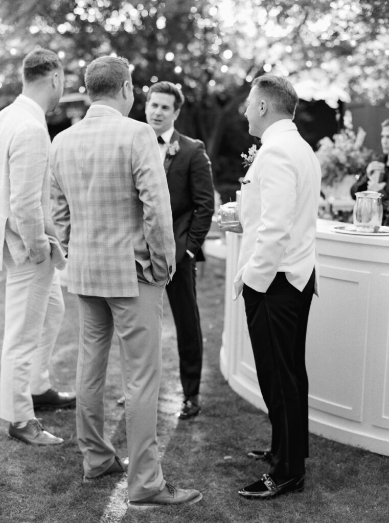 Black and white film photo of guys hanging out by the bar during cocktail hour. 