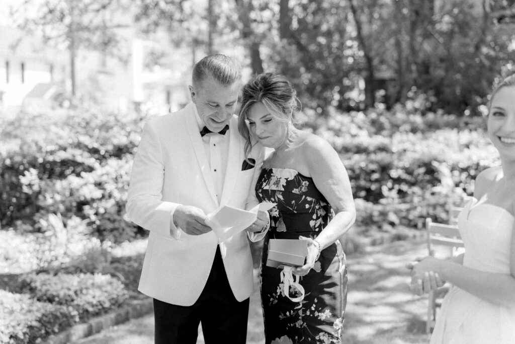 Black and white photo of parents of the bride reading a note from their daughter. 