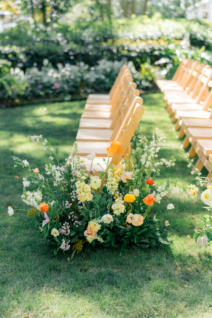 Spring wedding ceremony aisle flowers. Yellow with pops of orange. 