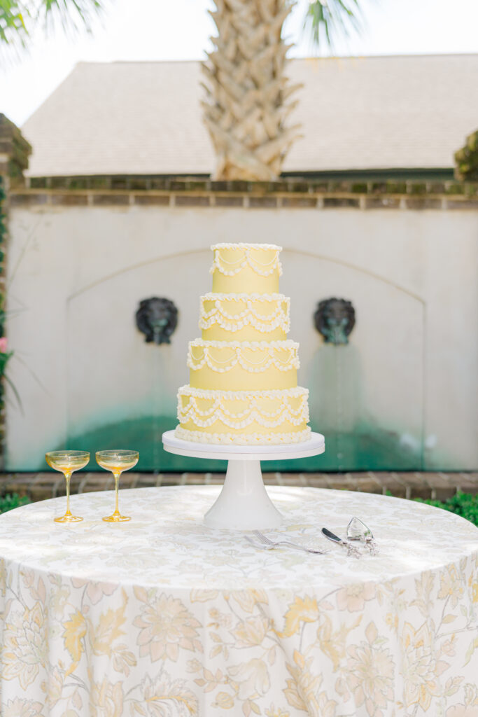 Yellow four tiered classic wedding cake with white piping. 