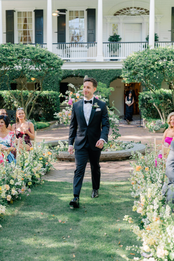 Groom smiles as he enters wedding ceremony at Thomas Bennett House. 