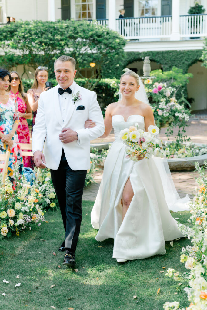 Father of the bride walks daughter up the aisle at spring garden wedding ceremony in downtown Charleston. 