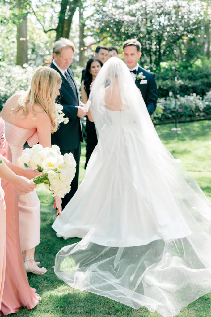 Maid of honor helps bride lay out her veil during wedding ceremony. 