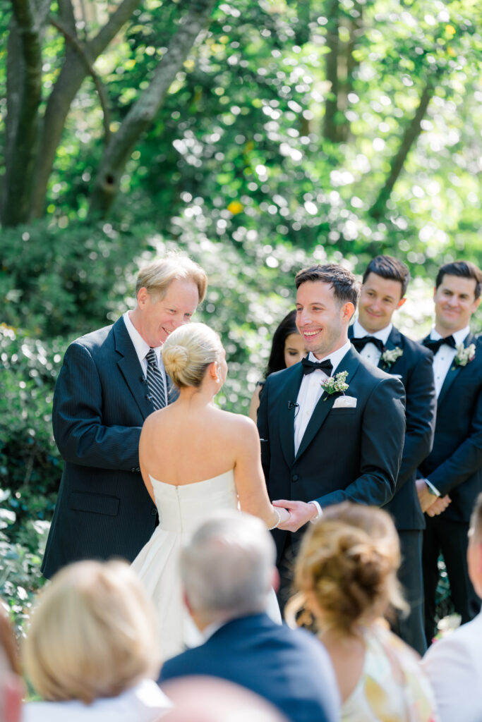 Groom smiles at bride during wedding ceremony vows. Governor Thomas Bennett House. 