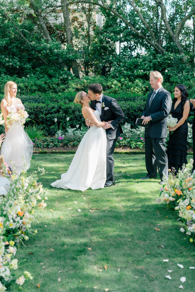 Bride and groom first kiss at outdoor spring wedding ceremony. 