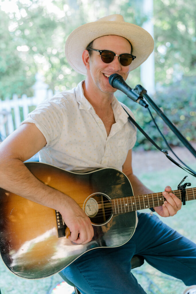 Live music at Beaufort Inn rehearsal dinner. Guitar player smiling and singing into microphone. 