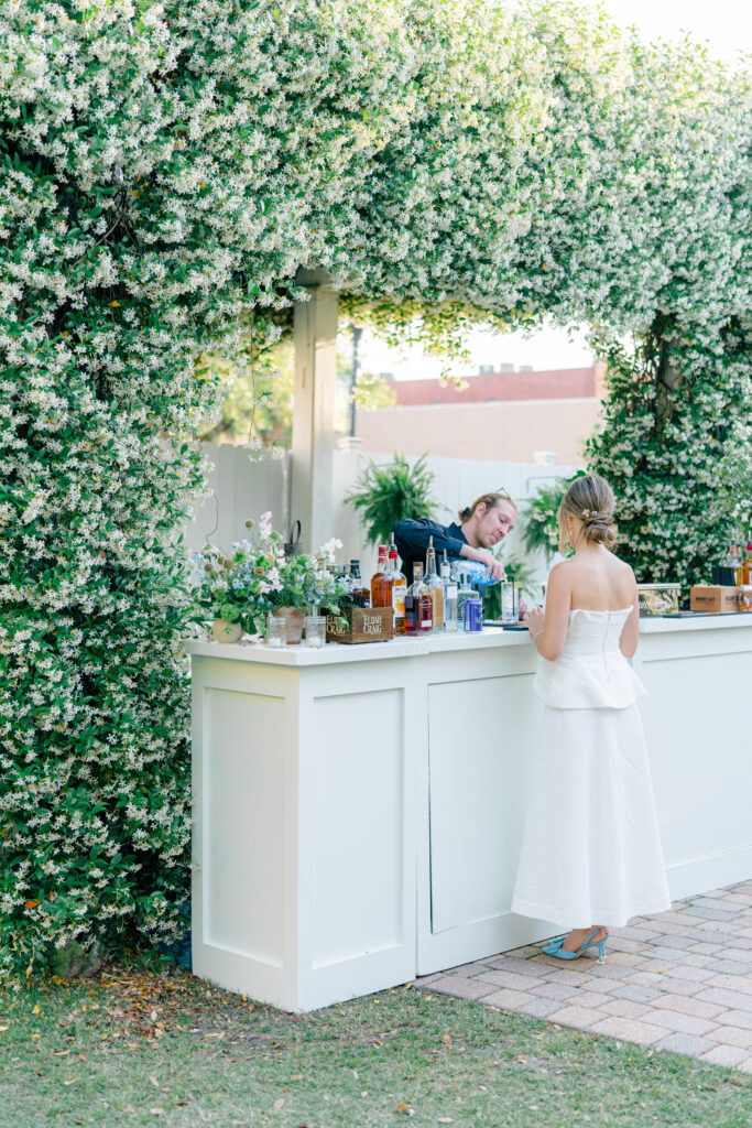 Bride heads to the bar to grab a drink. Blooming jasmine over the bar made a statement at spring rehearsal dinner at the Beaufort Inn. 