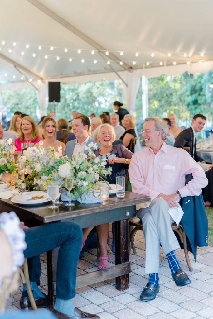 Parents of the groom laugh during wedding rehearsal dinner speech.