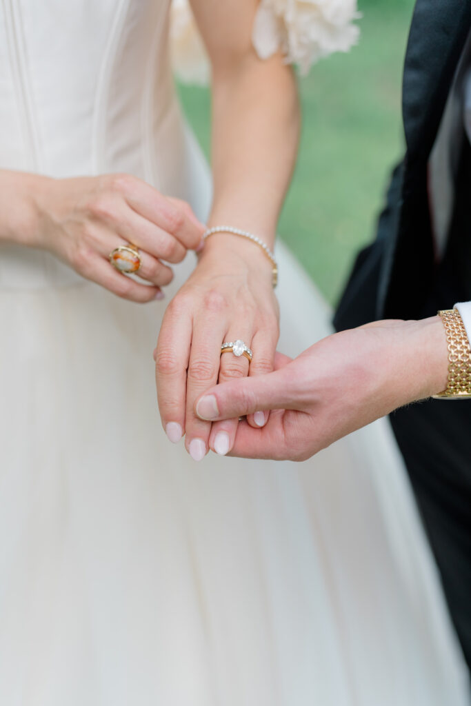 Groom holding brides hand. Each wearing family heirloom jewelry. 