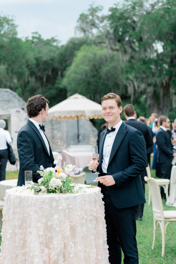 Wedding guest in a tux holding champagne. Spring Island destination wedding. 