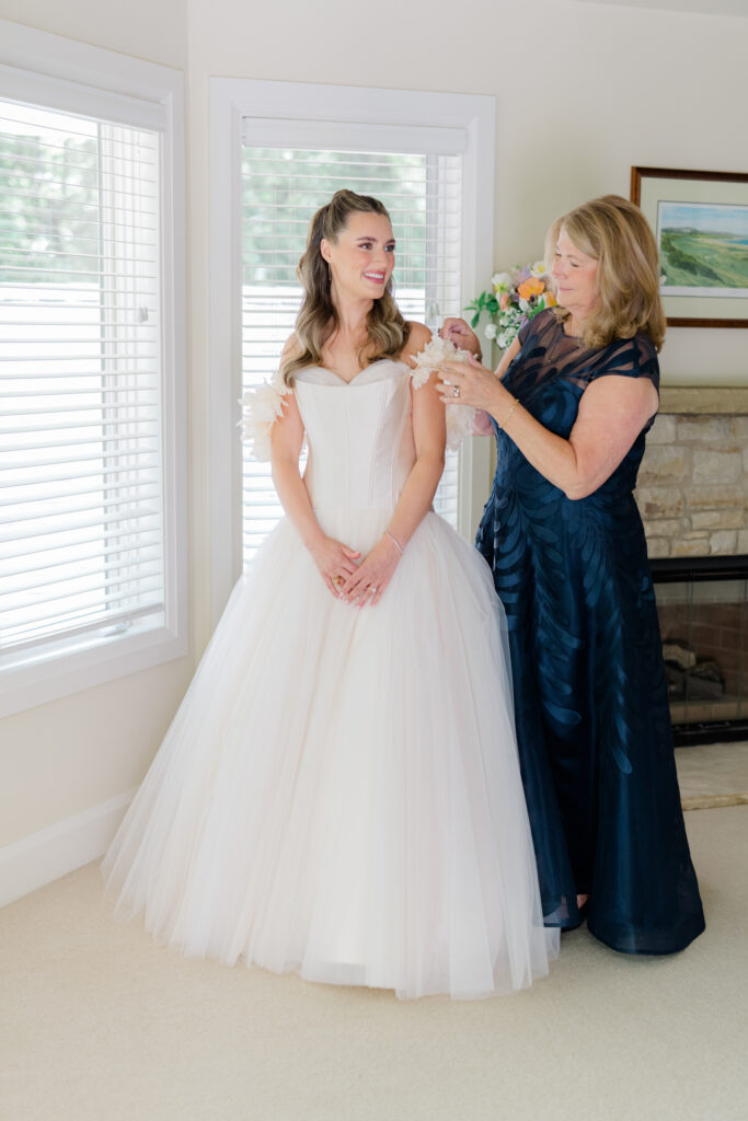 Mother of the bride fixes bride's statement floral sleeves. 