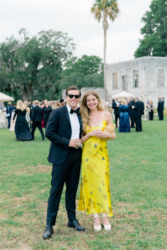 Wedding guest style. Guest wearing yellow dress. Guy in tuxedo and black sunglasses. 