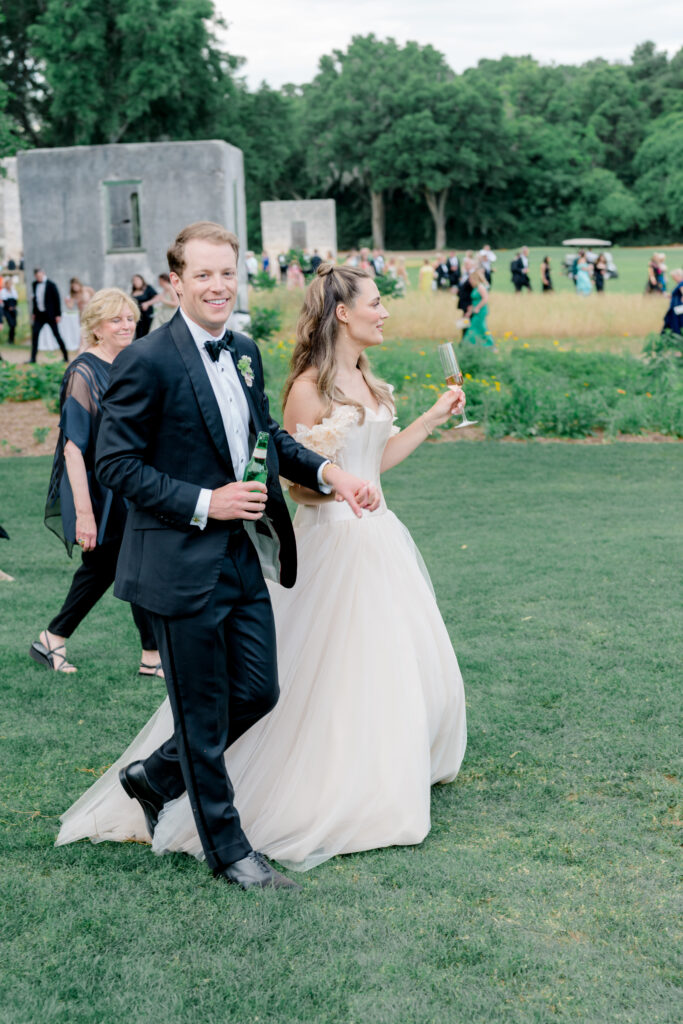 Bride and groom lead the way to wedding reception tent. 