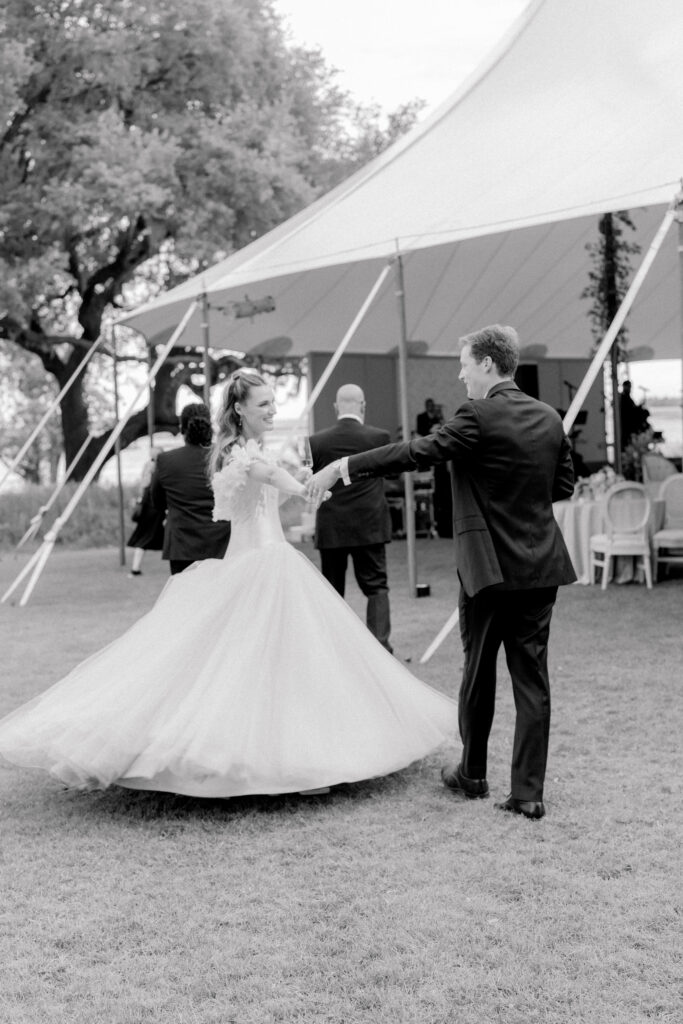 Black and white photo of groom spinning bride around. 