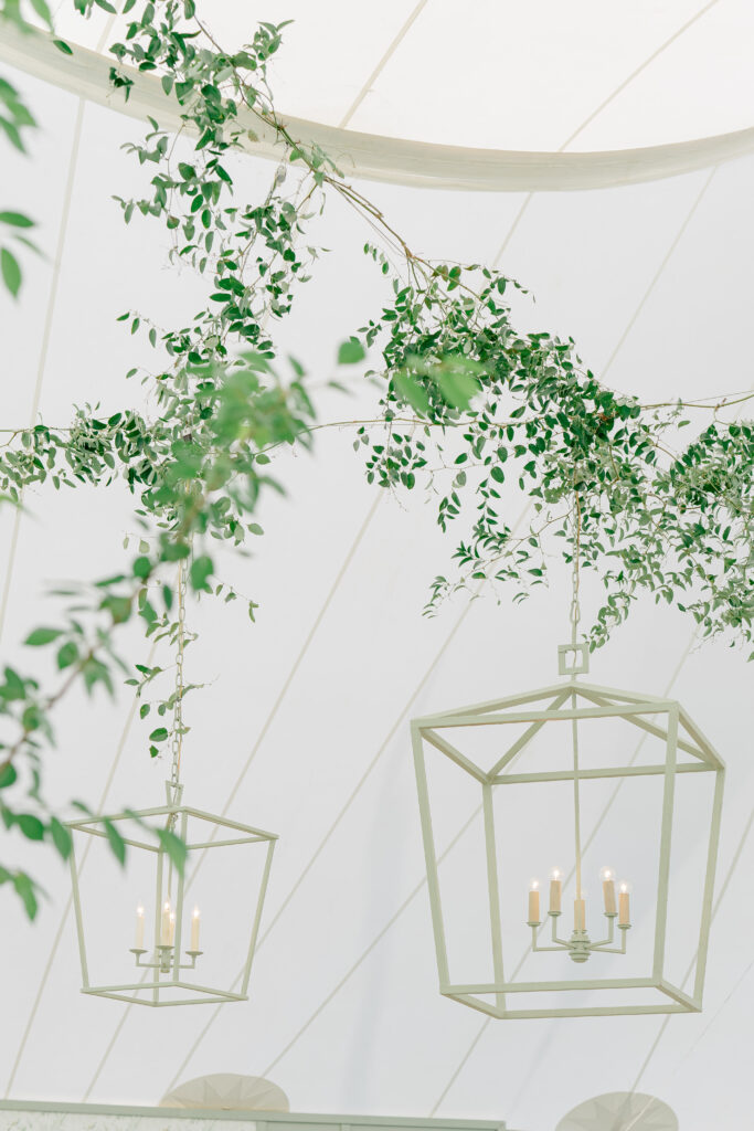 Light green lanterns hanging from tent at outdoor wedding reception. 