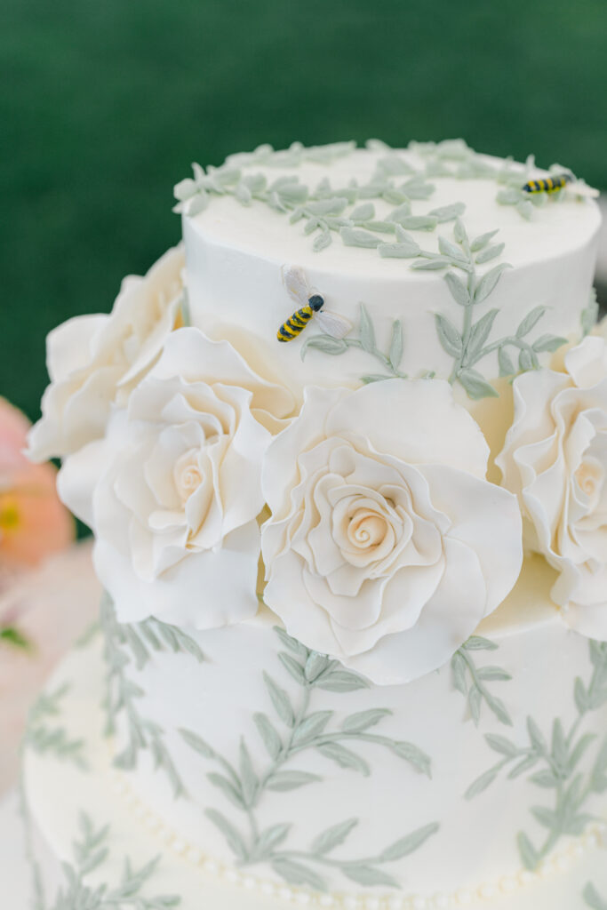 Green and white wedding cake with small bee design accent. 