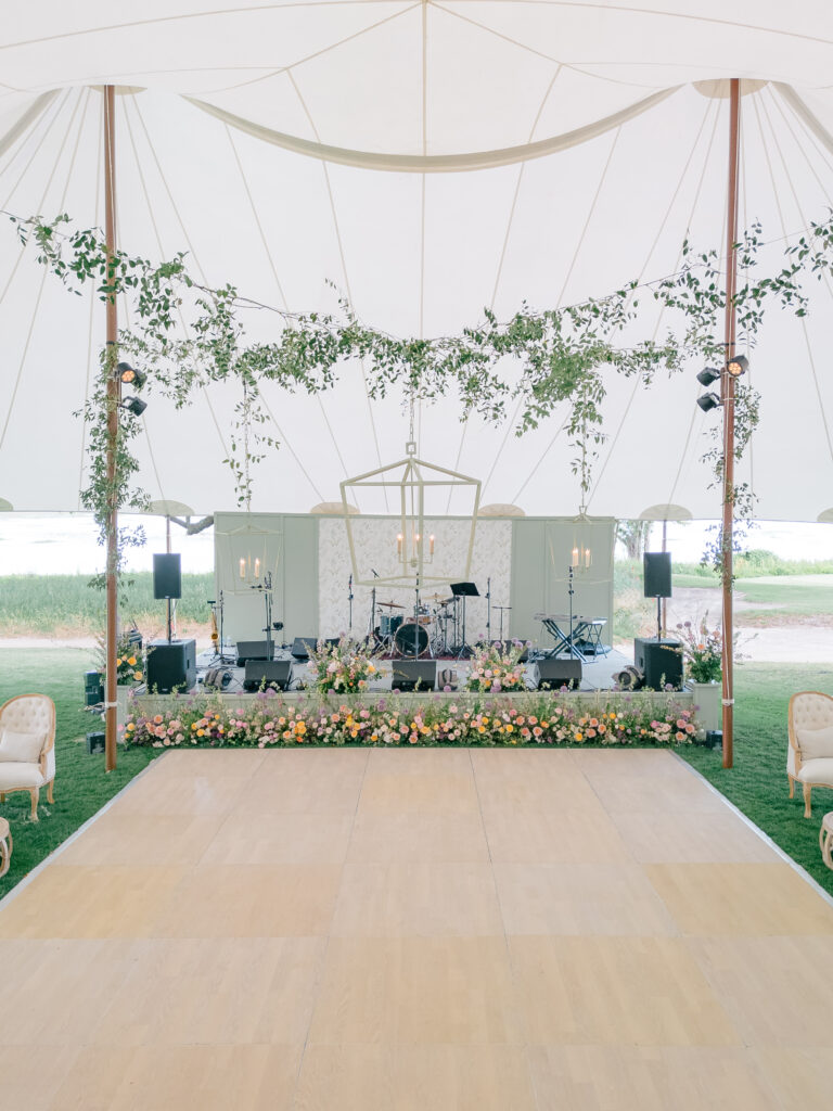 Grand tent design. Light green lanterns. Soft wood dance floor. Hanging greenery and lighting. 