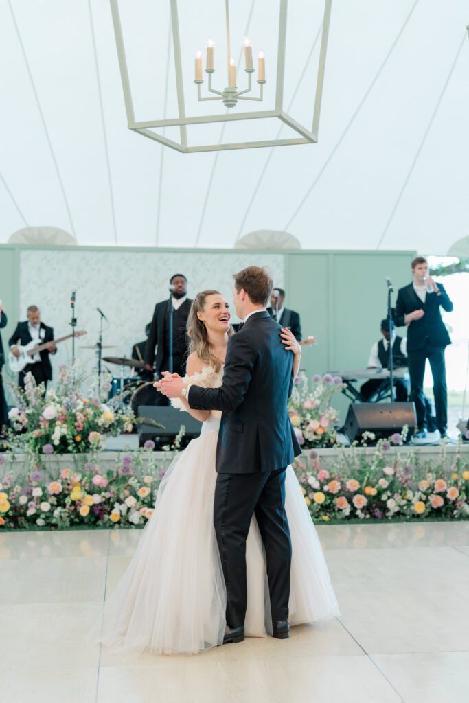 Bride and groom first dance at outdoor wedding reception with live band. 