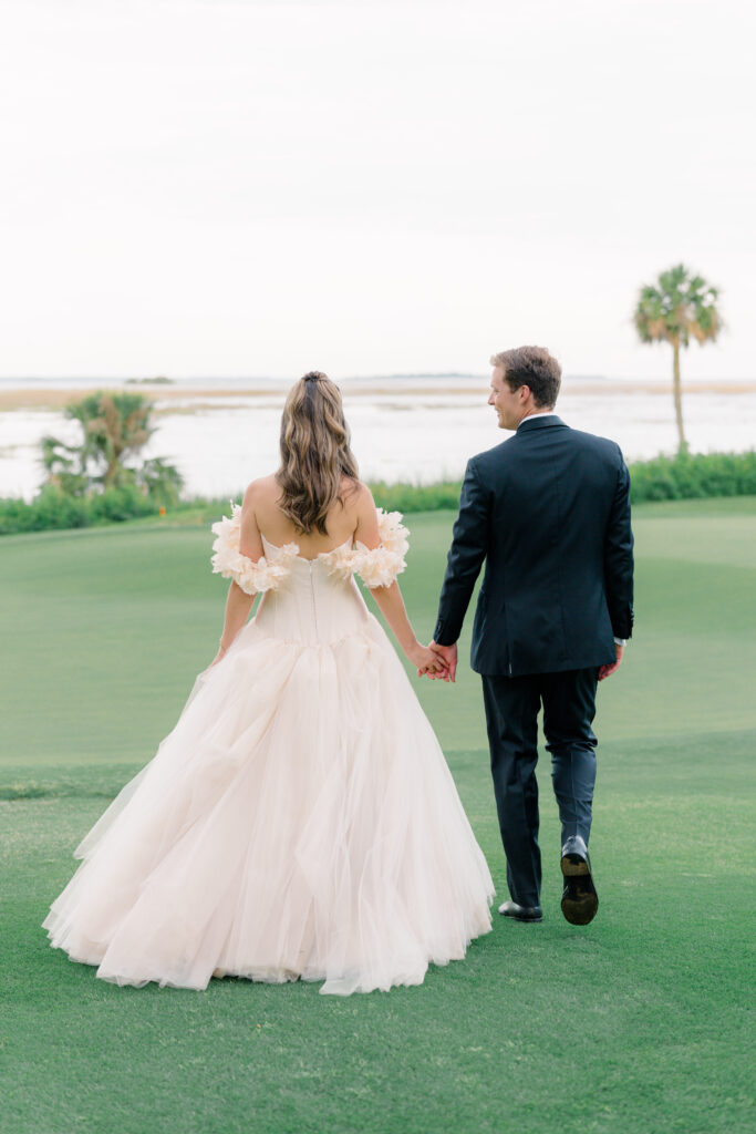 Bride and groom walking together away from camera. Groom looking at bride. 