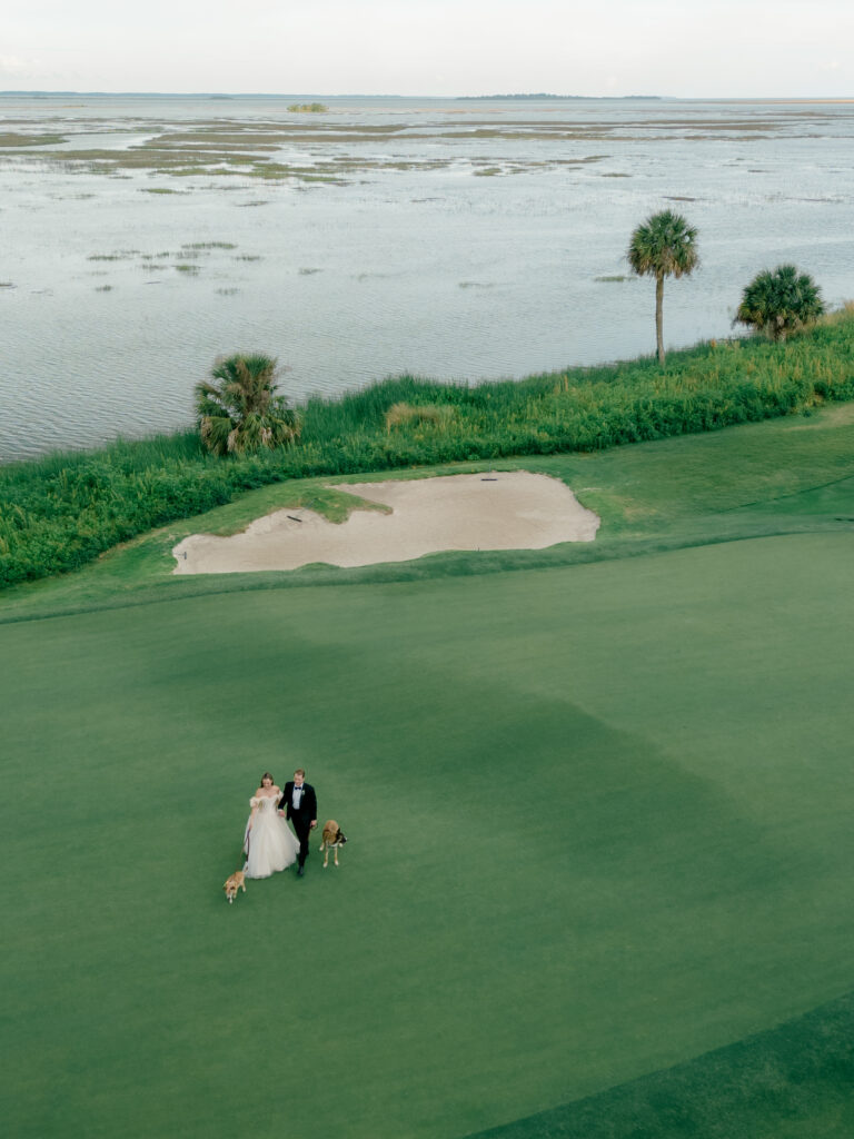 Bride and groom at the 18th hole with palm tree and water in background. 