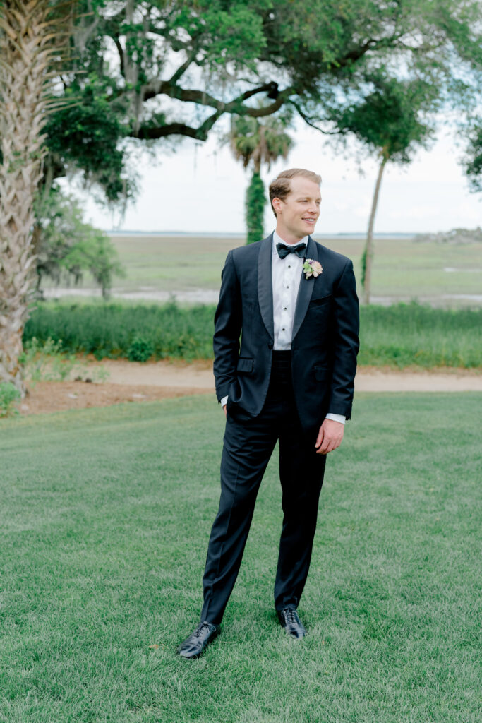 Groom standing on green grass. Wedding day portrait. 