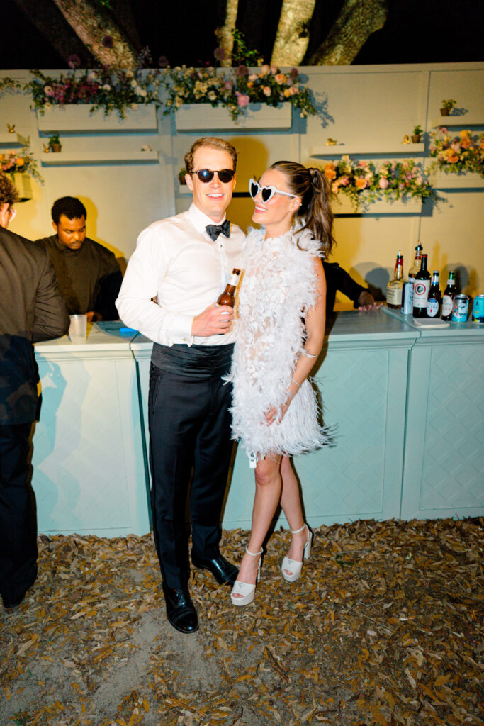 Bride and groom at the bar. Bride wearing white boa and white heart sunglasses. 