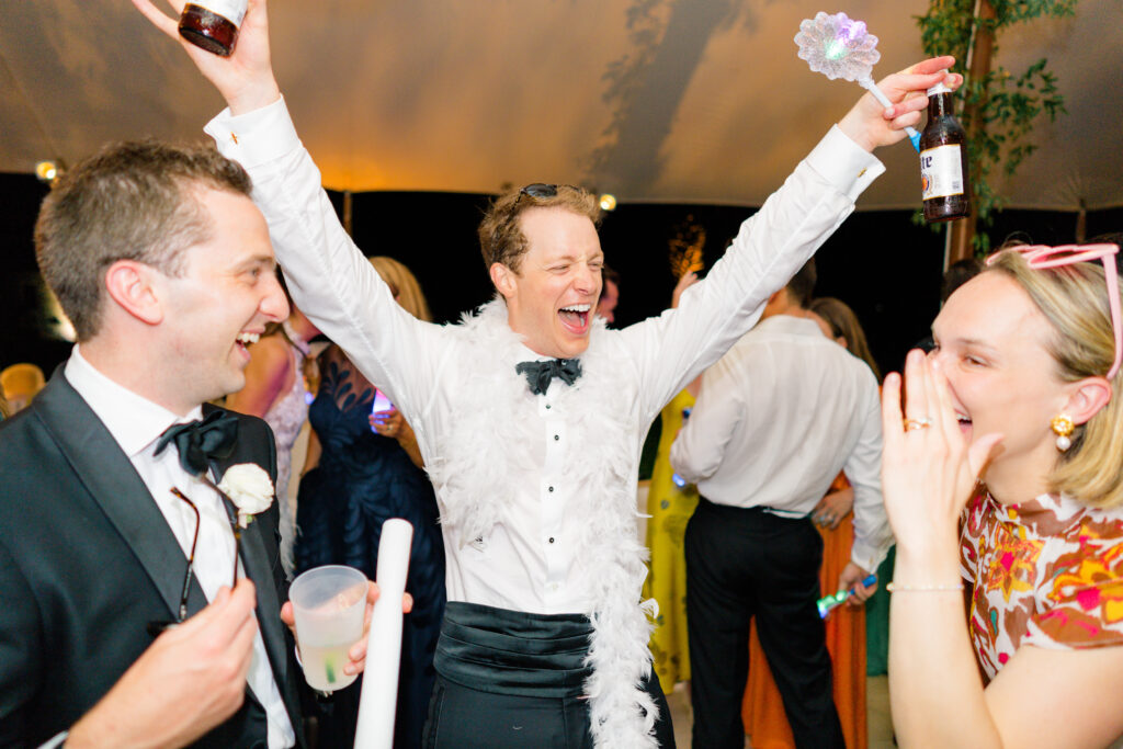 Groom laughing with wedding guests on dance floor. 