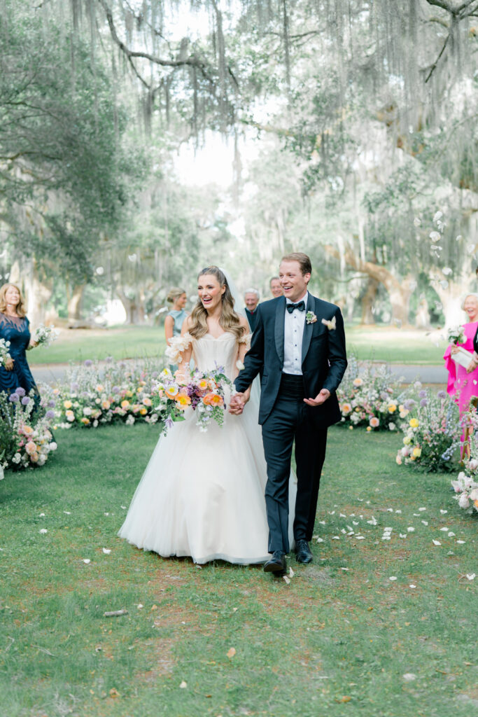 Flower petal toss wedding ceremony exit. Bride and groom celebrate with guests while walking down the aisle. 