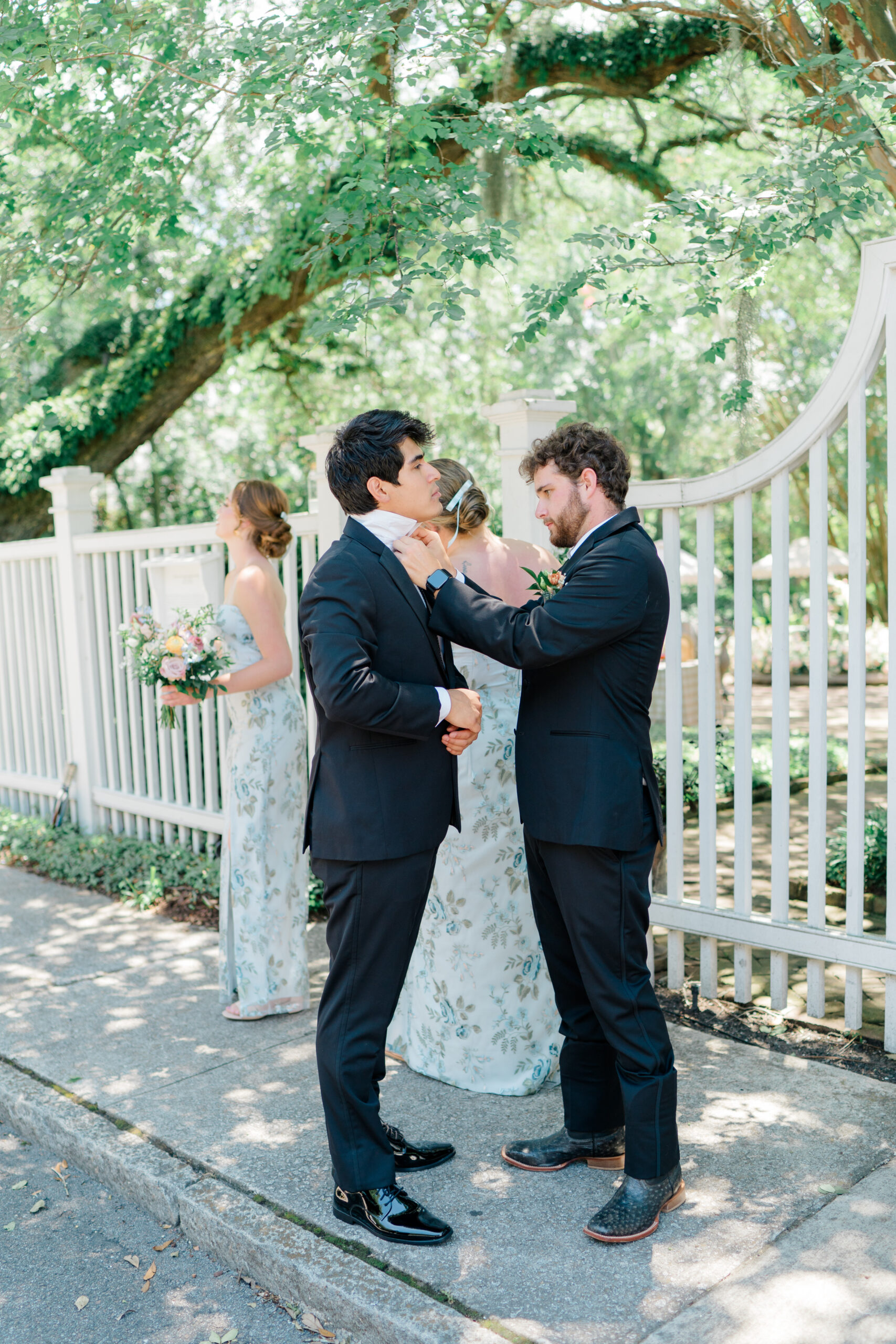 Groomsmen helping each other out with their collars on wedding day. 