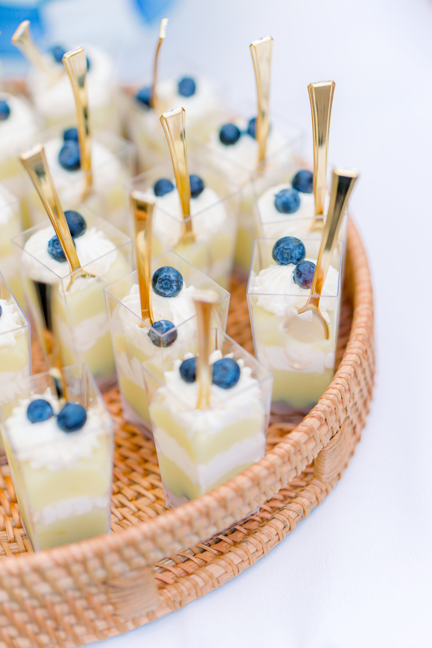 Small banana pudding deserts topped with blueberries and mini gold spoons. 