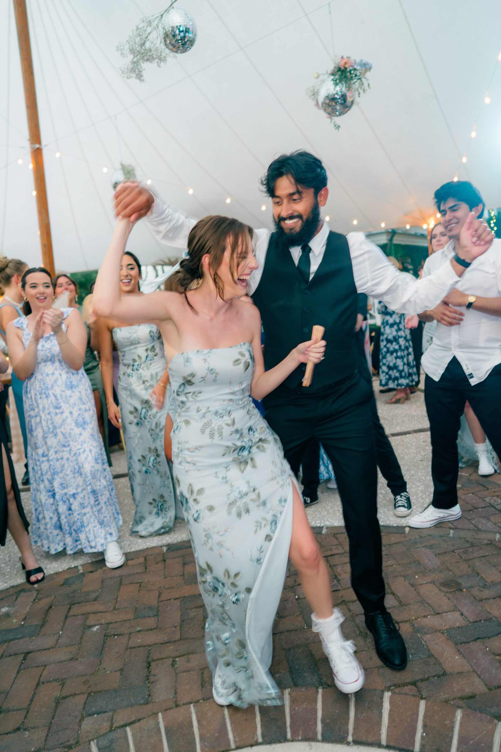 Fun on the dance floor. Guy spins girl around at outdoor wedding reception. 