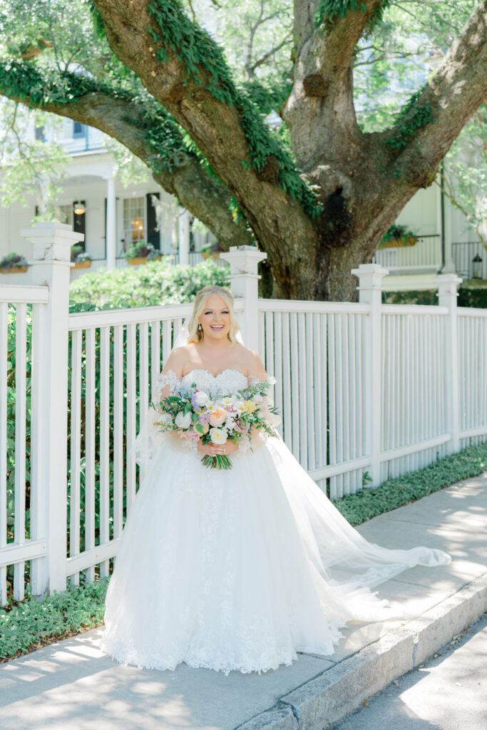 Bride giggling at Thomas Bennett House with tree covered in greenery in background. Charleston spring destination wedding.