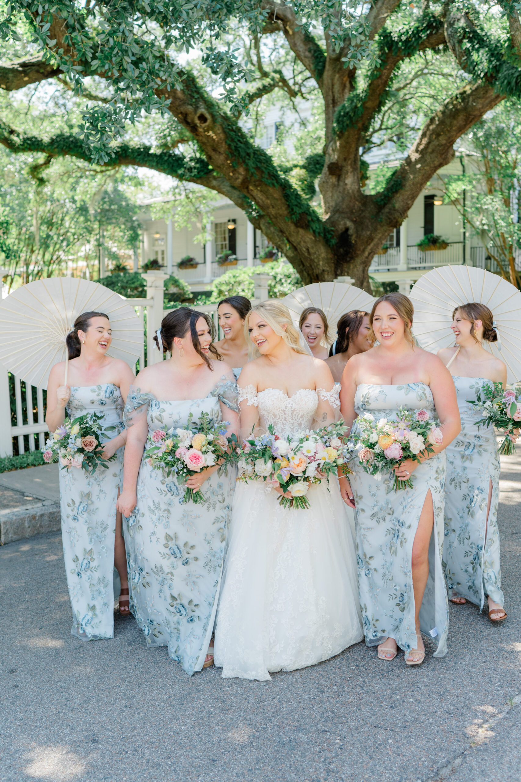 Bride and bridesmaids walking on the street and holding parasols. 